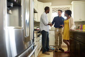 ServiceMaster restore professional standing in kitchen shaking homeowner's hand